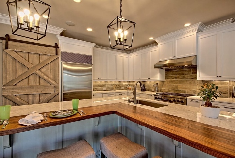 Beautiful modern kitchen with cabinets, marble island, pendant lights, and barn door in Duluth, GA