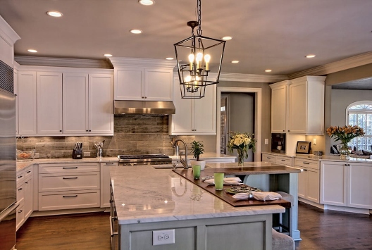 Modernistic, stylish kitchen with white cabinets, marble island, and  pendant lights in Duluth, GA