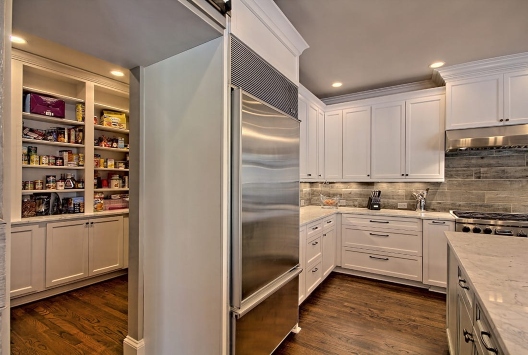 Modish kitchen with cabinets, stainless steel fridge, marble countertop, and pantry in Duluth, GA