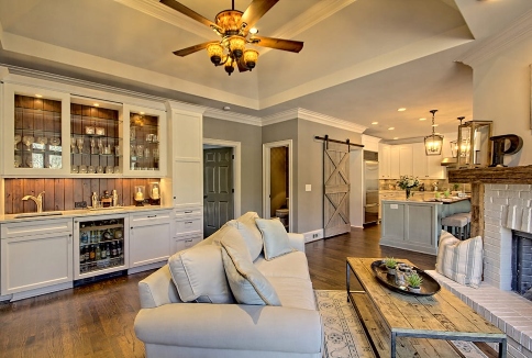 Living room with white sofa, rustic barn door, glass cabinets, and brick fireplace.