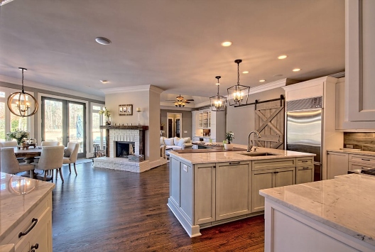 Spacious kitchen with island, dining area, and living room with white fireplace in Duluth, GA