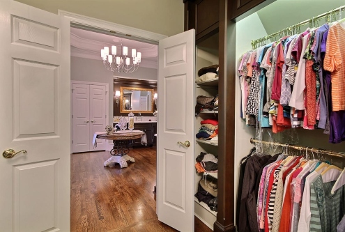 Walk‑in closet with organized shelving opening to a luxury dark wood vanity bathroom in Atlanta, GA
