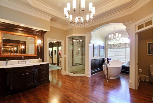 Luxury bathroom with chandelier, dark wood vanity, freestanding tub, and alcove in Atlanta, GA